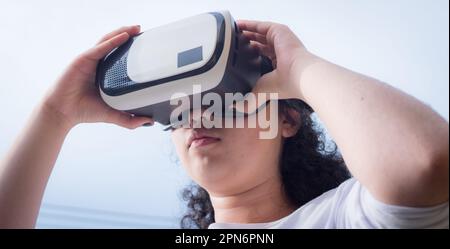 Junge Frau trägt eine Virtual-Reality-Maske an einem bewölkten Tag Stockfoto