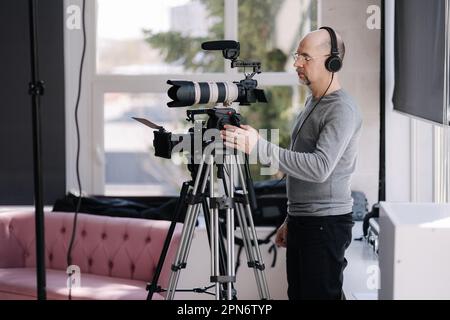 Ein professioneller Videofilmer zeichnet das Interview auf. Kameramann nimmt Video für Streaming-Dienste auf Stockfoto