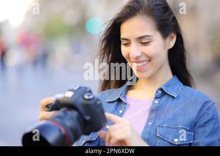 Glücklicher Fotograf, der Fotos auf der Straße überprüft Stockfoto