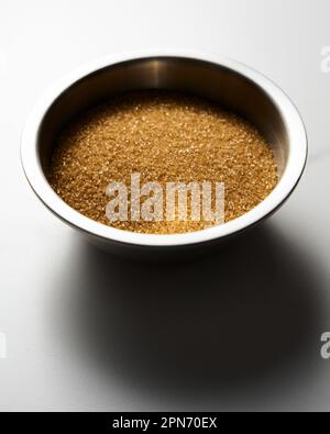 Brauner Zucker in einer Metallschüssel auf weißem Marmorhintergrund in der Küche. Stockfoto