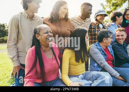 Eine Gruppe von Menschen, die mehrere Generationen haben und vor der Kamera lächeln – Freunde unterschiedlicher Rassen, die Spaß miteinander haben – Schwerpunkt auf Kaukasiern Stockfoto