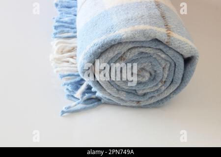 Karierte Wolldecke isoliert auf weißem Hintergrund. Weiß-blaue gerollte Decke. Stockfoto