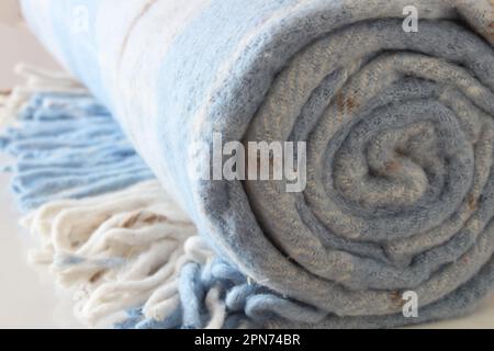 Karierte Wolldecke isoliert auf weißem Hintergrund. Weiß-blaue gerollte Decke. Stockfoto