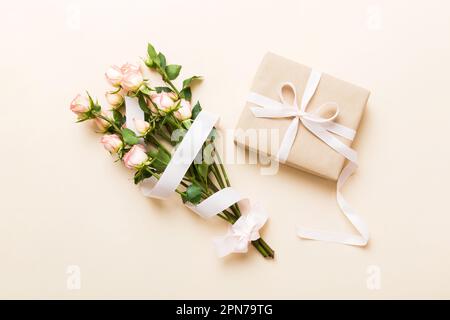 Designkonzept mit rosafarbener Rosenblume und Geschenkbox auf farbigem Tisch, Hintergrundansicht von oben. Frohe Feiertage, Muttertag, Geburtstagskonzept. Romantisches Flat la Stockfoto