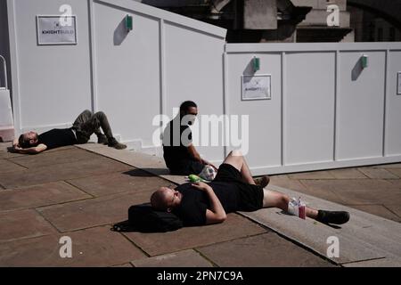 Bauarbeiter sonnen sich auf den Stufen nahe dem Trafalgar Square, während das warme Wetter London trifft. Foto: Montag, 17. April 2023. Stockfoto