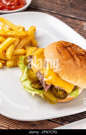 Köstlicher Rindfleischburger mit pommes Frites, Zwiebelringen und Saucen Stockfoto