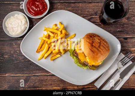 Köstlicher Rindfleischburger mit pommes Frites, Zwiebelringen und Saucen Stockfoto