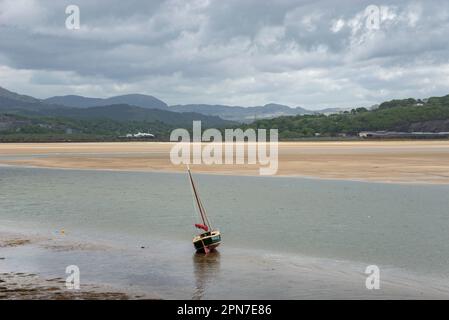 Boot in der Mündung von Glaslyn in Borth-y-gest, Nordwales mit einem Zug auf der Ffestiniog-Bahn in der Ferne. Stockfoto