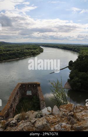 Blick auf eine Flussbiegung in der Donau, von der Burg Devin (Slowakei) in Richtung Österreich; ein Teil der Burgruinen ist im Vordergrund zu sehen Stockfoto