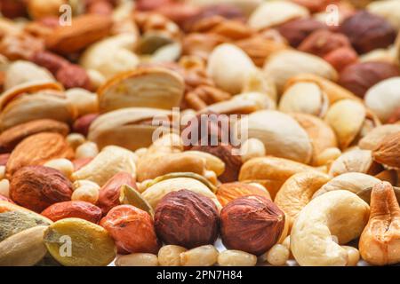 Verschiedene Arten von Nüssen und Samen, Foto mit selektivem Fokus. Geschälte Walnuss, Haselnüsse, geschälte Erdnuss, Pinienkerne, Mandelkerne, Cashewkerne, Stockfoto