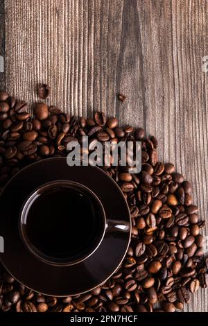Foto auf Kaffeebohnen steht eine Tasse Kaffee auf Holzhintergrund Stockfoto