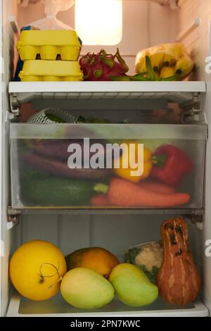 Offener Kühlschrank mit frischem Gemüse, Obst und Eiern Stockfoto