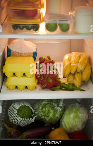 Frische Lebensmittel im offenen Kühlschrank, Obst, Eier und Gemüse Stockfoto