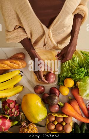 Frau, die frisches Obst und Gemüse in Kunststoffbehältern verpackt und im Kühlschrank aufbewahrt Stockfoto