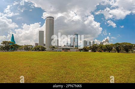 Fotografieren Sie die historische Sportanlage Padang in Singapur mit der Skyline im Hintergrund während des Tages Stockfoto