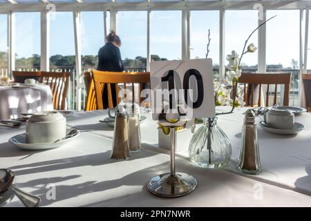 Tisch 10 in einem Hotelrestaurant mit sauberer Tischdecke und Tassen und Untertassen, die für Gäste zum Frühstück bereit stehen. Stockfoto