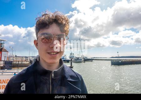 Ein Teenager mit Sonnenbrille posiert für ein Porträt am Kai in Poole Harbour, Dorset, Großbritannien Stockfoto