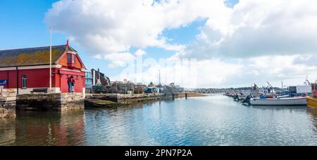 Ein Blick auf Boote, die im Hafen von Poole in Dorset, Großbritannien, vor Anker liegen, mit dem alten roten RNLI-Rettungsboothaus auf der linken Seite. Stockfoto