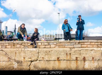 Touristen am Kai am Poole Harbour in Dorset, Großbritannien. Eine Familie ist beim Krabbenfischen, während eine andere hält und Fotos macht. Stockfoto