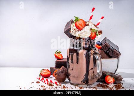 Milchshake mit doppeltem Schokoladengeschmack. Verrückter Shake mit Brownie-Geschmack, Schokoladensoße, Schlagsahne und frischen Erdbeeren, sommerlich süßes, geladenes Swe Stockfoto