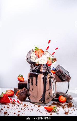 Milchshake mit doppeltem Schokoladengeschmack. Verrückter Shake mit Brownie-Geschmack, Schokoladensoße, Schlagsahne und frischen Erdbeeren, sommerlich süßes, geladenes Swe Stockfoto