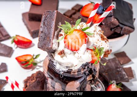 Milchshake mit doppeltem Schokoladengeschmack. Verrückter Shake mit Brownie-Geschmack, Schokoladensoße, Schlagsahne und frischen Erdbeeren, sommerlich süßes, geladenes Swe Stockfoto