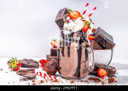 Milchshake mit doppeltem Schokoladengeschmack. Verrückter Shake mit Brownie-Geschmack, Schokoladensoße, Schlagsahne und frischen Erdbeeren, sommerlich süßes, geladenes Swe Stockfoto