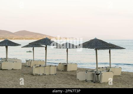 Blick auf Holzschirme und Sonnenliegen am mediterranen Strand Stockfoto