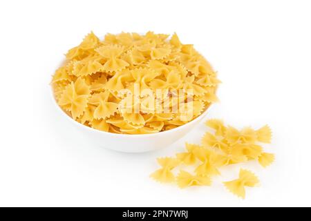 Farfalle in Schüssel und isoliert auf weißem Hintergrund. Rohe Pasta in Spiralform, Zutaten für den Koch, traditionelle italienische Küche. Stockfoto