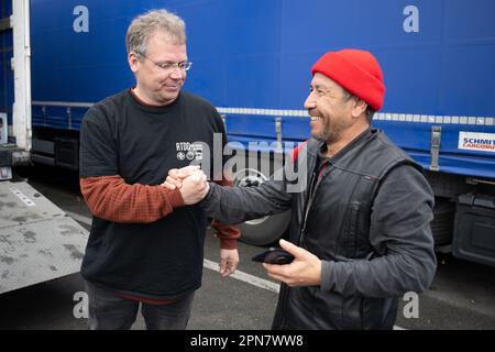 PRODUKTION - 17. April 2023, Hessen, Weiterstadt: Edwin Atema (l), niederländischer Gewerkschafter der FNV und des Road Transport Due Diligence Teams (RTDD), schüttelt sich bei einem Streik von Lkw-Fahrern eines polnischen Logistikunternehmens im Servicegebiet Gräfenhausen die Hand mit dem Lkw-Fahrer Erkinjon, der soeben Geld vom Logistikunternehmen erhalten hat. Die Lkw-Fahrer fordern seit mehreren Wochen ausstehende Löhne von ihrem Arbeitgeber. Die ersten Fahrer haben bereits einen Teil ihres Gehalts erhalten, aber eine große Zahl wartet noch. Foto: Sebastian Gollnow/dpa Stockfoto