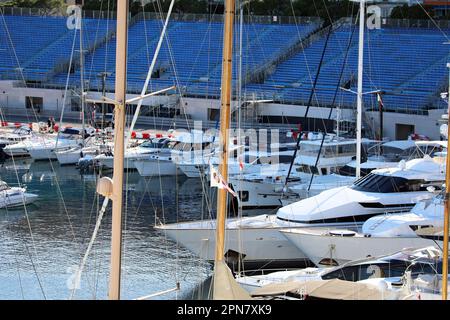 Monte-Carlo, Monaco - 16. April 2023: Zahlreiche Luxusboote und Yachten in Port Hercule, Monte-Carlo, Monaco, mit Formel 1 Grand Prix blauer Haupttribüne Stockfoto