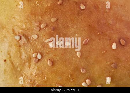 Nahaufnahme von frisch gebackenem Brötchen oder Brot mit Sesamkörnern auf der Oberseite, goldbrauner und knuspriger Snackplatte, vollflächiger Essenshintergrund Stockfoto