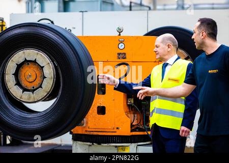 Hannover, Deutschland. 17. April 2023. Während seines Besuchs erfährt Bundeskanzler Olaf Scholz (SPD, l) vom Continental-Werk über die Runderneuerung von Lkw- und Busreifen und spricht mit einem Mitarbeiter. Kredit: Moritz Frankenberg/dpa/Alamy Live News Stockfoto