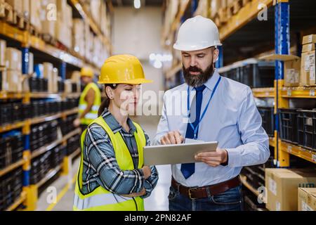 Manager erklärt seinen Arbeitgebern im Lager die Arbeit. Stockfoto