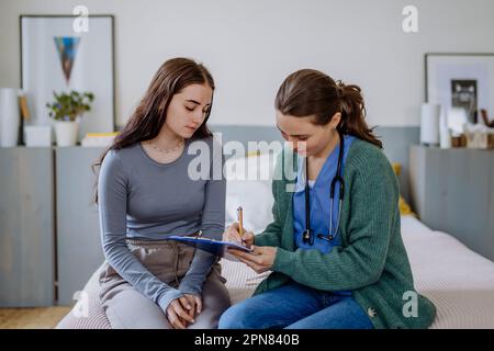 Teenager mit Magenschmerzen, junger Arzt untersucht sie. Stockfoto