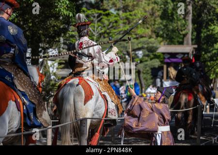 Der offizielle Yabusame-Turnier (japanische Bogenschießen) gibt nach dem Ende der ersten Runde einen Pfeil zurück zu den Bogenschützen. Zum ersten Mal nach 4 Jahren kehrt das Kamakura Festival zurück, und damit auch das Yabusame-Turnier (japanisches Bogenschießen). Yabusame ist eine Sportveranstaltung, deren Ursprünge bis 300 v. Chr. (Jomon-Zeit) zurückreichen. Zuerst zu Fuß, dann aus dem 4. Jahrhundert, begannen die Konkurrenten, Pferde zu benutzen. Ursprünglich schossen die Bogenschützen in Duellen aufeinander. Heute werden Ziele verwendet. Stockfoto