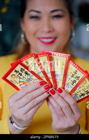 Asiatische Frau mit roten Umschlägen ( hongbao ) zur chinesischen und vietnamesischen Neujahrsfeier. Rot ist ein Glückssymbol. Frankreich. Stockfoto