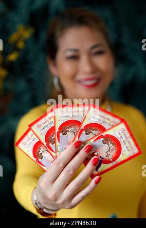 Asiatische Frau mit roten Umschlägen ( hongbao ) zur chinesischen und vietnamesischen Neujahrsfeier. Rot ist ein Glückssymbol. Frankreich. Stockfoto