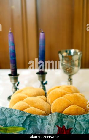 Schabbat mit Challah-Brot auf einem Holztisch Kerzen und eine Tasse Wein. Traditionelles jüdisches Sabbat-Ritual. Sabbat Shalom. Stockfoto