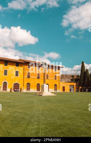 Pisa, Italien - 18. März 2023: Palazzo dell'Opera Palast, Angelo Caduto Statue, Lupa capitolina Denkmal auf einem Platz mit grünem Rasen, blauem Himmelsweiß Stockfoto