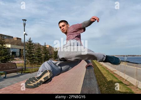 Sportler, der Parkour im städtischen Raum praktiziert. Parkour-Sportler, der über das Geländer springt. Aktiver Lifestyle. Akrobatik im Freien Stockfoto