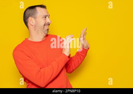 bärtiger hispanischer Mann in seinen 40s Jahren, der einen roten Pullover trug, der zur Seite stand und seine Hände zum Schutz benutzte, völlig beschämt und peinlich. Isoliert Stockfoto