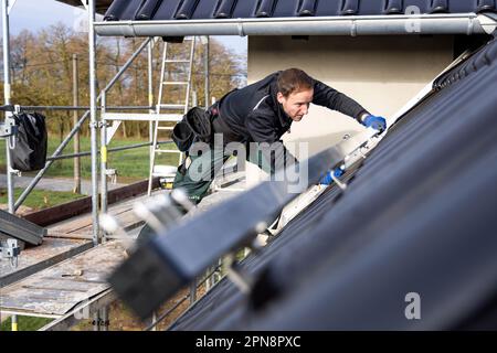 Handwerker, der Solarpaneele auf dem Dach eines deutschen Einfamilienhauses installiert Stockfoto