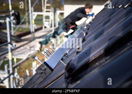 Installation von Unterkonstruktionen für Sonnenkollektoren auf einem Fliesendach Stockfoto