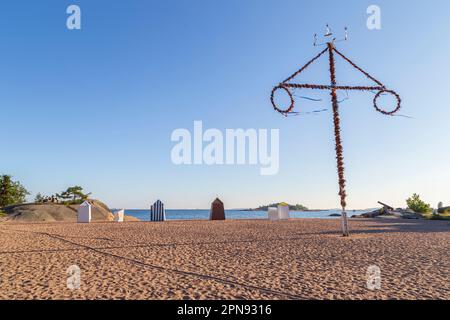 Wickeltische oder Hütten aus Holz und traditionelle Mittelsommer-Stangen am leeren und sandigen Kasinastrand im Zentrum von Hanko, Finnland, an einem sonnigen Tag im Sommer Stockfoto