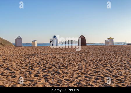 Hölzerne Umkleidekabinen oder Hütten am leeren und sandigen Casino-Strand in der Innenstadt von Hanko, Finnland, an einem sonnigen Tag im Sommer. Stockfoto