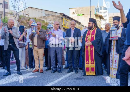 Haifa, Israel - 15. April 2023: Priester und Einheimische tragen das heilige Feuer während einer Parade am Heiligen Samstag, die Teil der orthodoxen Osterfeier in Haifa ist, Stockfoto