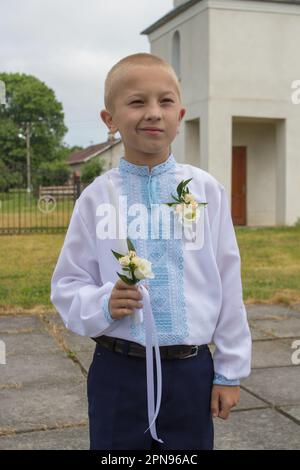 Ein kleiner Junge feiert seine erste heilige Kommunion Stockfoto