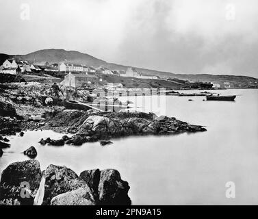 Ein Blick aus dem späten 19. Jahrhundert auf Roundstone, ein Dorf an der Westküste Irlands, in der Connemara-Region der Grafschaft Galway. Roundstone wurde in den 1820er Jahren vom schottischen Ingenieur Alexander Nimmo gegründet, während er Häuser, Straßen und Häfen im Westen Irlands baute. Fischer aus Schottland siedelten sich hier an, und 1835 wurde ein Franziskanerkloster gebaut. Ende 1840er hatte sie eine florierende Fischwirtschaft und eine Bevölkerung von 400 Einwohnern. Stockfoto