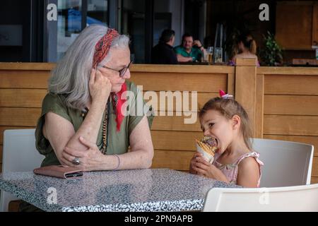 Ein kleines Mädchen wird von ihrer Oma in einer Eisdiele in Rotorua, Nordinsel, Neuseeland, mit einem Eis verwöhnt Stockfoto